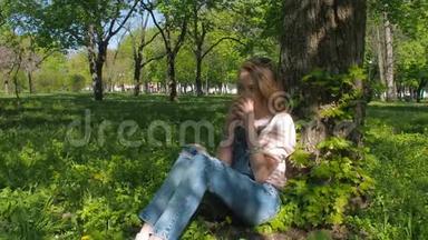 一个年轻<strong>女孩</strong>正在公园里喝咖啡。 阳光明媚的一天，<strong>女孩</strong>在<strong>清新</strong>的空气中。 一个穿着牛仔服的少年正坐在树下