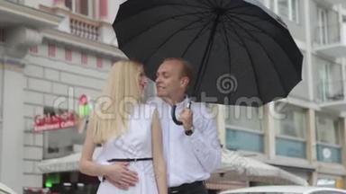 男人和女人拿着雨伞站在他们的车附近。 城里漂亮的一对。 黑色雨伞。 黑白衣服