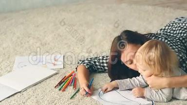小女孩用铅笔画一幅画。 妈妈拥抱和亲吻她。