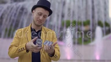 穿着黄色夹克的魔术师手里拿着扑克牌