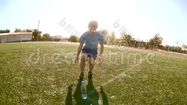 小男孩足球运动员在训练期间从塑料瓶里喝水。 青少年踢足球