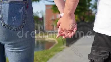 亲密的两个情人携手。 男女牵手在公园散步的细节剪影。 夫妇