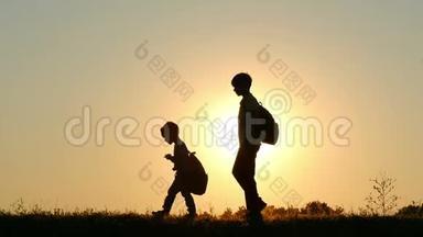 两个孩子在日落时背着背包<strong>走路</strong>的<strong>剪影</strong>。