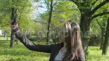 一个十几岁的女孩自拍。 公园里的女孩正在拍照。 一个十几岁的女孩在公园里带着电话。