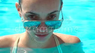 一位<strong>女士</strong>戴着镜子<strong>太阳镜</strong>，里面反射着游泳池的蓝色水