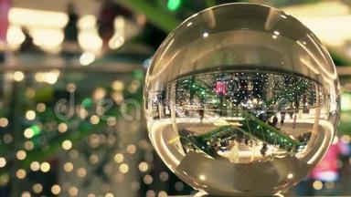 顾客在圣诞节和新年装饰购物中心。 透过玻璃球扭曲的视野