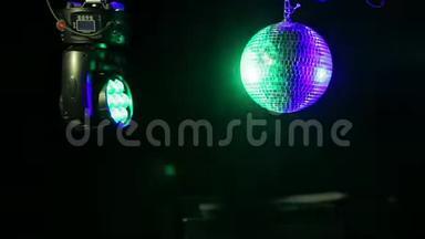 蓝色和绿色探照灯的定向光束照射在黑色背景上的镜面迪斯科球