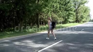 带着背包的年轻女子穿过马路。 在路上行走的女人