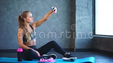 一个<strong>身材好</strong>的年轻女孩在健身房的手机上自拍