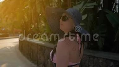 一个戴着蓝色帽子的漂亮女孩去热带城市。 夏日的阳光。