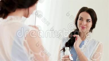 漂亮的年轻女人在镜子前用棉签和保湿乳液做面部护理