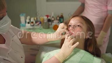 一个戴乳胶手套的牙医用金属工具在一个十几岁的孩子身上<strong>磨牙</strong>