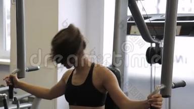 年轻女子在室内健身房的PEC<strong>甲板</strong>机上做运动。