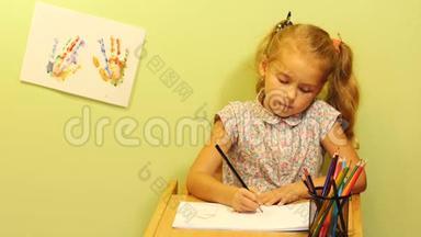 <strong>可爱</strong>的女孩坐在桌子旁画着家庭肖像。 有头发尾巴的女孩<strong>画画</strong>。 画幸福的家庭..