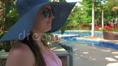 戴着蓝色帽子的漂亮女孩走到<strong>游泳</strong>池旁的休息室。 <strong>夏日</strong>阳光