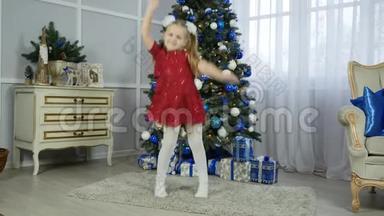 一个穿<strong>红裙子</strong>的小女孩正在圣诞树旁跳舞