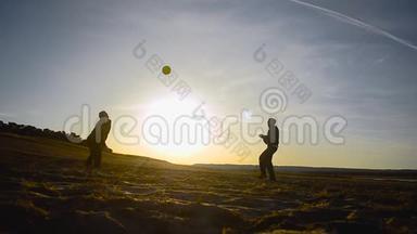 训练男子在阳光下在沙滩上打排球，在春天的傍晚在沙滩上打排球