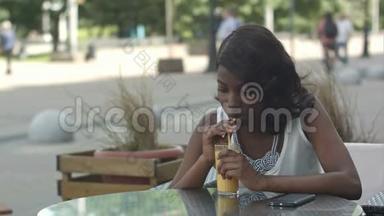 非洲年轻女子一边喝橙汁一边在咖啡馆里做梦的肖像