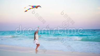 可爱的小女孩在热带海滩放风筝。 孩子在海边玩美丽的日落