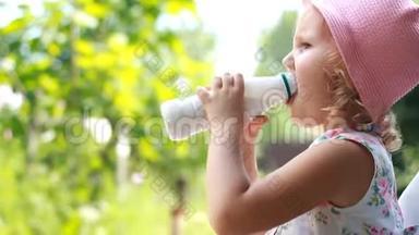 小女孩喝一瓶牛奶或开菲尔，微笑着，露出了酸奶的白胡子。