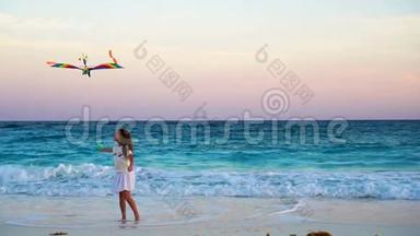 可爱的小女孩在热带海滩上放风筝。孩子们在美丽的日落下的<strong>海边玩耍</strong>。慢动作。
