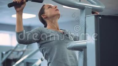 女人在重力仪上做拉力运动来<strong>加强</strong>健身房的肩部肌肉