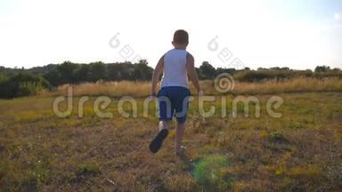 在阳光明媚的日子里，小男孩在草地上奔跑。 快乐微笑的男孩子在大自然中享受乐趣