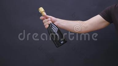 男人`黑色背景上拿着一瓶香槟的手