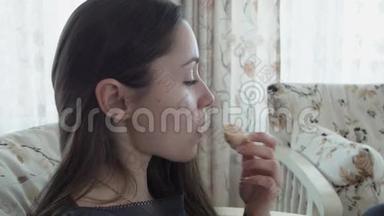 一个可爱的年轻女人吃<strong>羊角</strong>面包的肖像。 年轻漂亮的女人早上吃<strong>羊角</strong>面包。 早餐