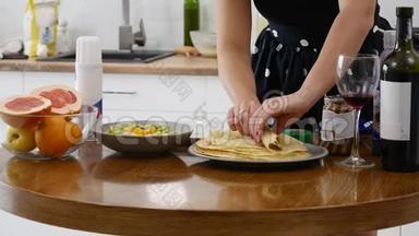 女人的手紧紧地`在煎饼上放馅。 在木制圆桌上烹制国家美食