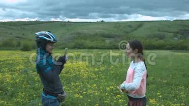 两个美丽的旅游女孩在花圃上使用智能手机拍照。 一个戴头盔的年轻女子