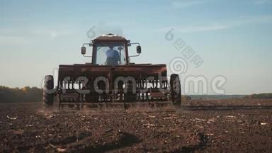 拖拉机耙地的全景。农用拖拉机播种和耕作田。拖拉机在田间作业