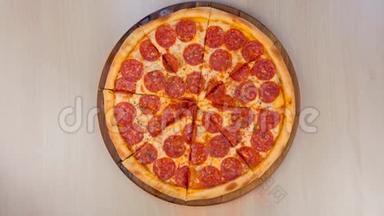 把意大利腊肠披萨切在桌子上的木板上。 特写俯视图..