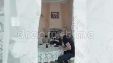一对<strong>幸福</strong>美丽的年轻夫妇正坐在明亮的客厅的桌子旁。 年轻家庭的早餐，在前面