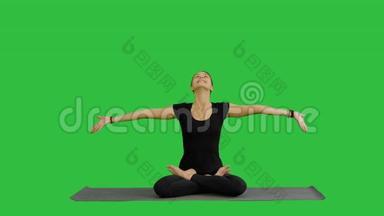 年轻女子在绿色屏幕上练习瑜伽时进行冥想，Chroma键