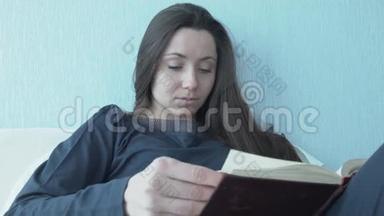 年轻女子坐在床上看书，<strong>望</strong>着<strong>窗外</strong>。 美丽的年轻女子躺在床上看书