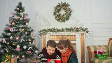 圣诞节和新年主题。 一对年轻夫妇互相喜欢拔罐热咖啡。 一间有圣诞树的房间