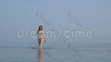 热辣的美女走在海里.. 优雅吸引人的女孩正在腿上溅起水滴