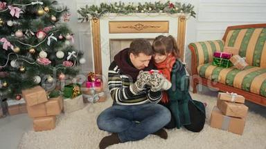 圣诞节和新年主题。 一对年轻夫妇互相喜欢拔罐热咖啡。 一间有圣诞树的房间