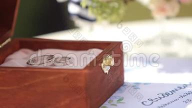 桌子上的木箱里放着<strong>白金</strong>结婚<strong>戒指</strong>的宏观镜头。 户外婚礼装饰。