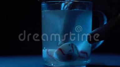 僵尸`手从装有液体的玻璃烧杯中取出眼睛