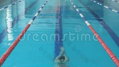 蓝水室内泳池泳蝶泳泳姿年轻女子泳镜及泳帽慢动作