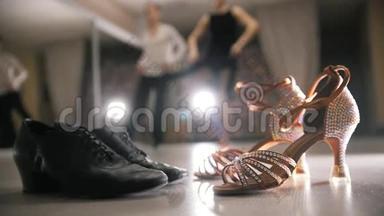 模糊的职业男女舞蹈拉丁舞服装在工作室，两双舞厅鞋在前景