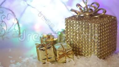 带雪和丝带的金色礼盒。 圣诞节寒假装饰，用抽象的闪亮的薄纱装饰