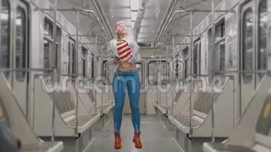 那个有趣的迷人的、快乐的金发女孩在地铁的地铁里跳舞。 女人为成功而高兴
