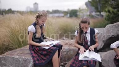 一群穿着相同校服的<strong>学生</strong>在户外看书时坐着<strong>聊天</strong>