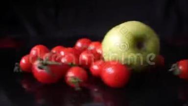 红樱桃西红柿和绿苹果在黑色背景上快速旋转。
