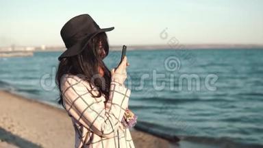 年轻女子正在手机上给女朋友拍照。 女孩在户外拍照
