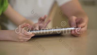 小女孩的手在平板触摸屏上打字，父女俩在用app