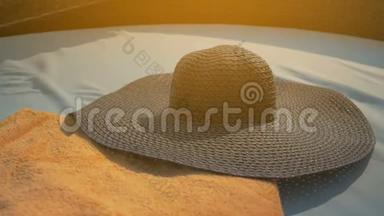 漂亮的女孩正戴着一顶蓝色的帽子，躺在躺椅上。 夏日的阳光。 慢动作。